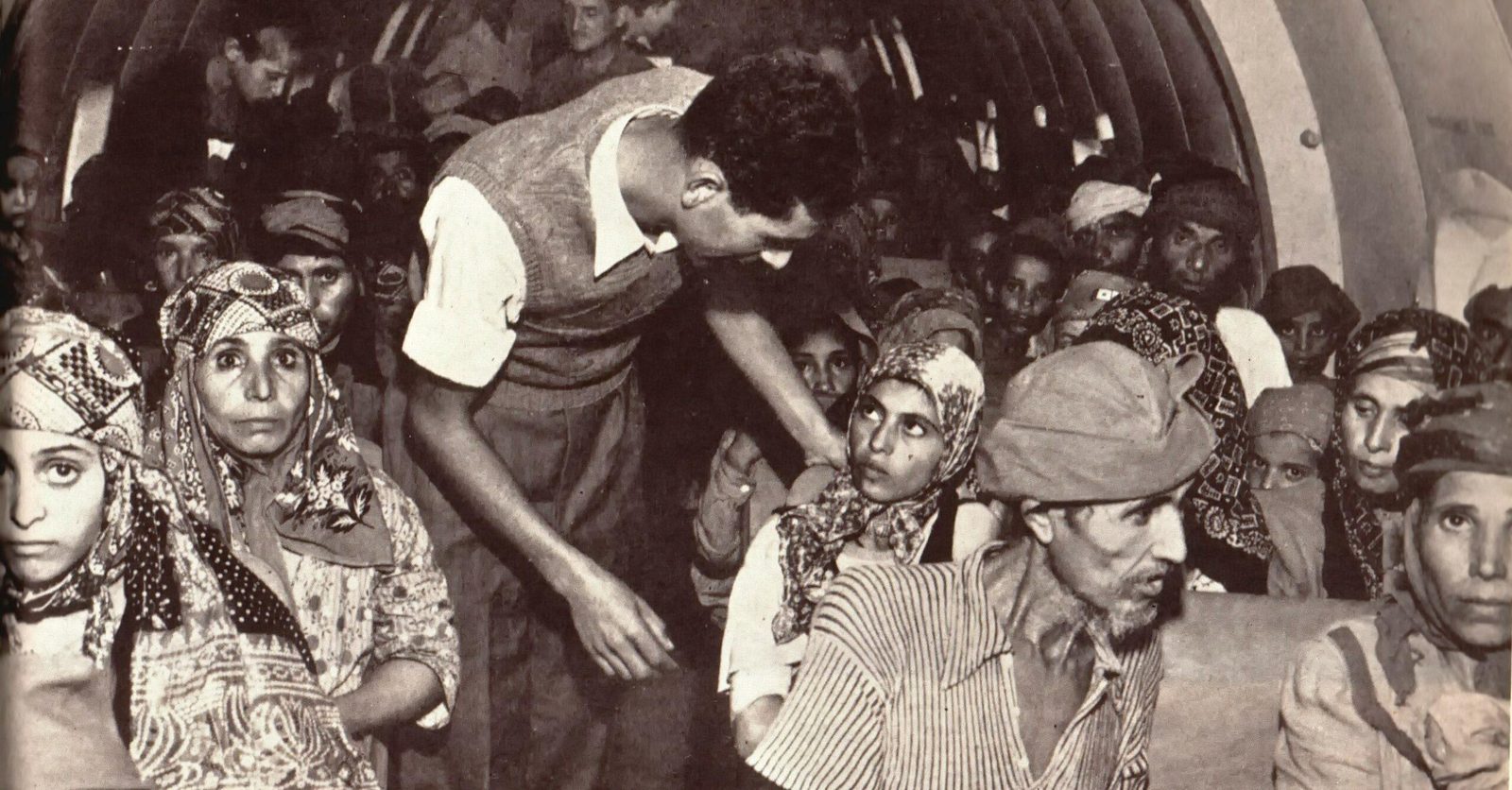 Jewish refugees from Arab and Muslim countries seated closely together inside an aircraft during an airlift to Israel.